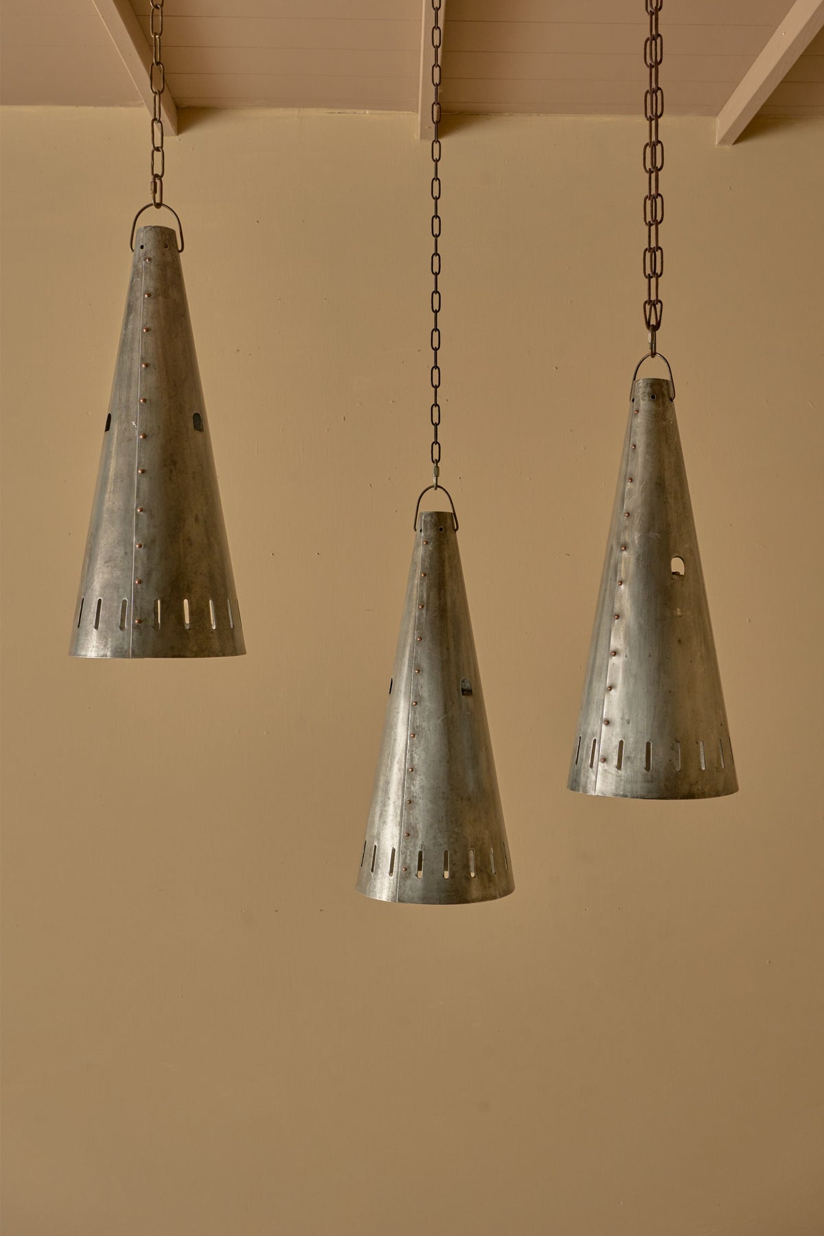 Trio of 20th century patinated steel and copper rivet conical pendant lights